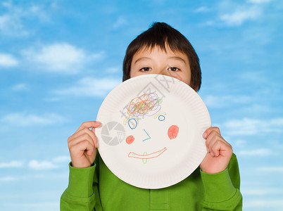 一个男孩拿着一个上面画着一幅图画的纸盘图片