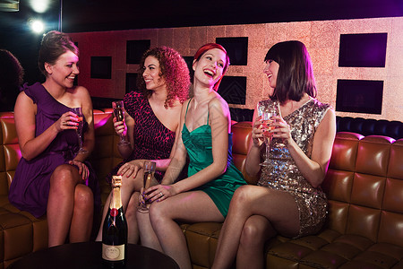 女孩们晚上出去玩在夜总会里喝香槟的四个年轻女人背景