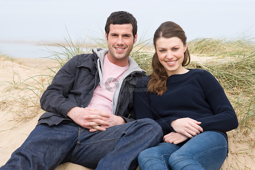 一对夫妇坐在沙滩上的沙滩上图片