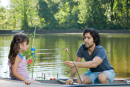 父亲和女儿带着鱼竿在划艇上图片