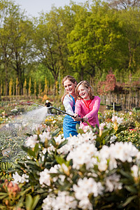 花园管女人和女孩用水管浇花背景