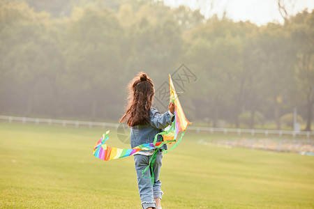 秋天小女孩夕阳下小女孩草坪上放风筝背影背景