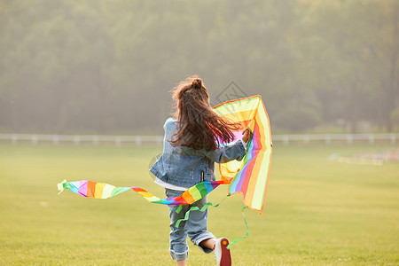 运动夹克夕阳下小女孩草坪上放风筝背影背景