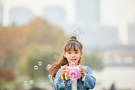 小女孩草地上玩泡泡机图片