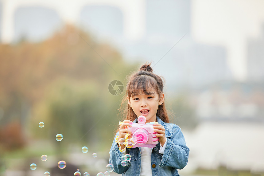 小女孩草地上玩泡泡机图片