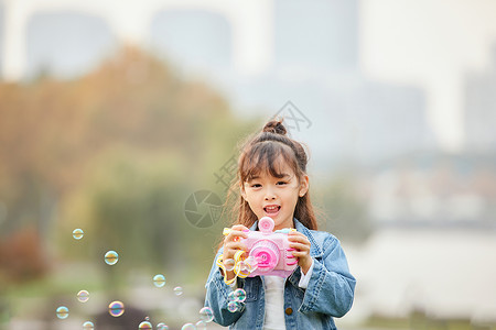 粉色泡泡小女孩草地上玩泡泡机背景