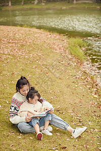 温馨母女坐在草地上看书高清图片