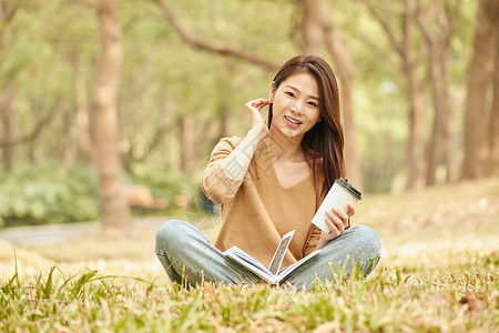 年轻女性草地上看书喝咖啡图片