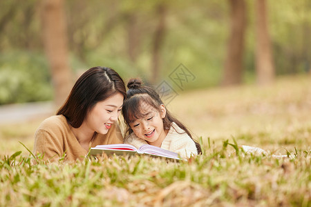 母女趴在草地上读书高清图片
