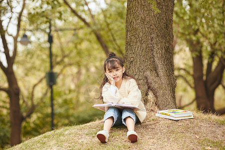 小女孩坐在树下读书图片