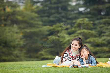 春游季节母女趴在草地上阅读背景