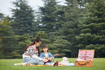 春游季节母女在草地上弹尤克里里背景