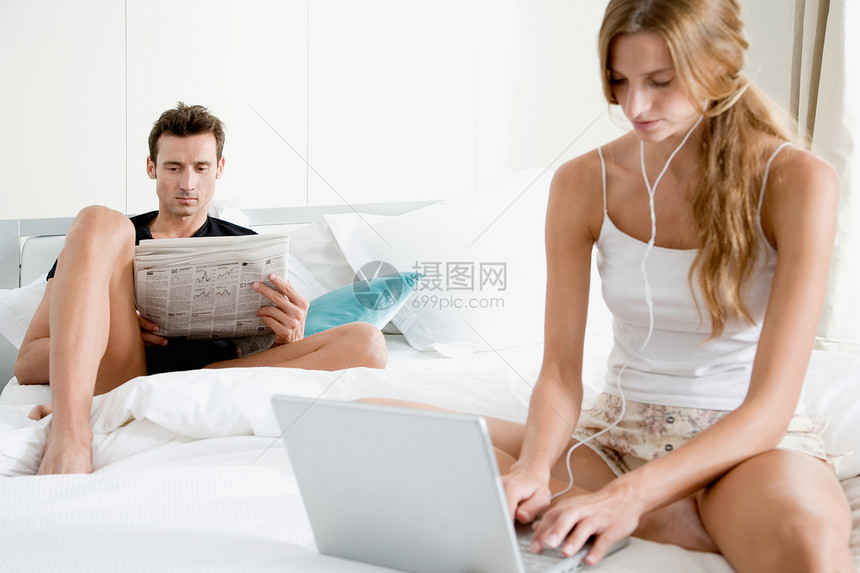 带报纸和笔记本的夫妇在床上图片