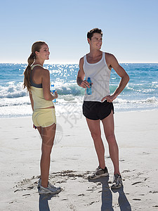 海滩上拿着瓶装水的年轻夫妇图片