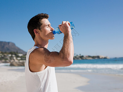 男人喝水年轻人在海滩上喝水背景