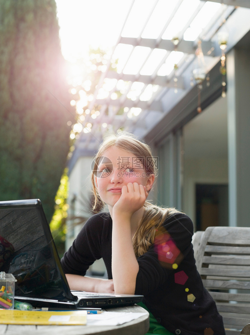 年轻女孩在花园里的笔记本电脑前思考图片