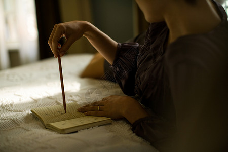 女人躺在酒店房间的床上写日记图片