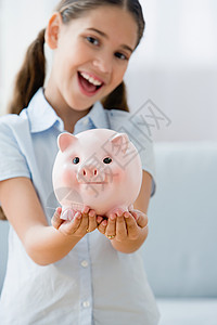 抱着小猪存钱罐微笑的女孩图片