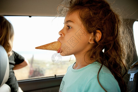 口含冰淇淋蛋卷的年轻女孩高清图片