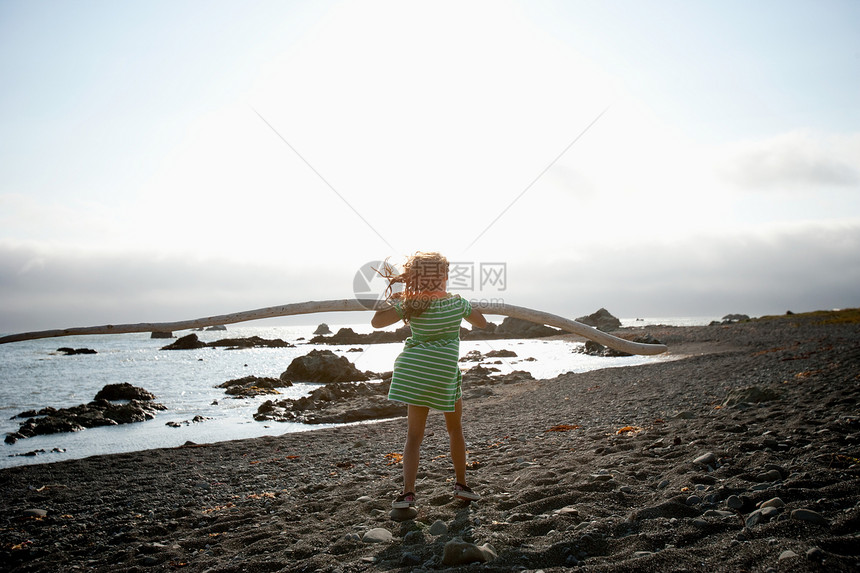 站在海滩上抱着浮木的女孩图片