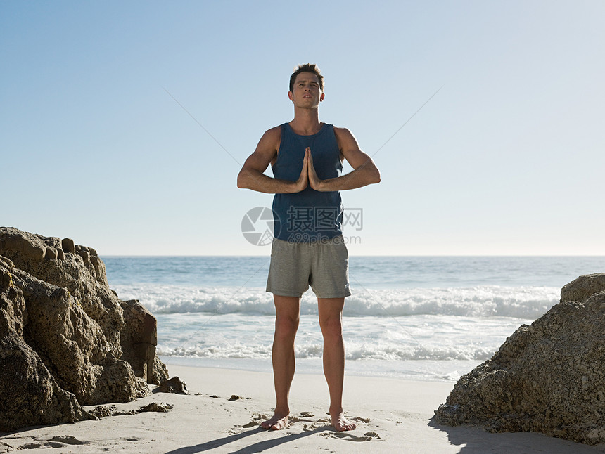 在海滩上做瑜伽的年轻人图片