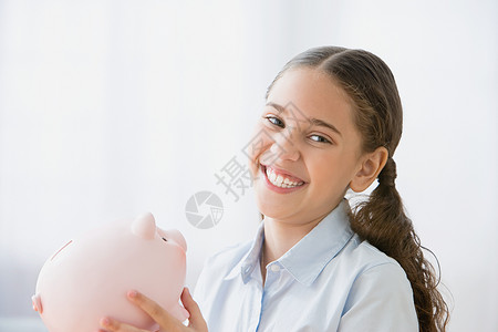拿着小猪存钱罐微笑的女孩图片