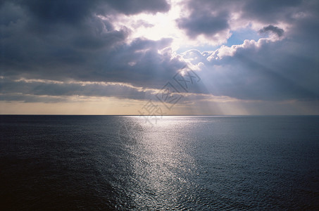 透过云层的阳光阳光透过云层照射在海面上背景