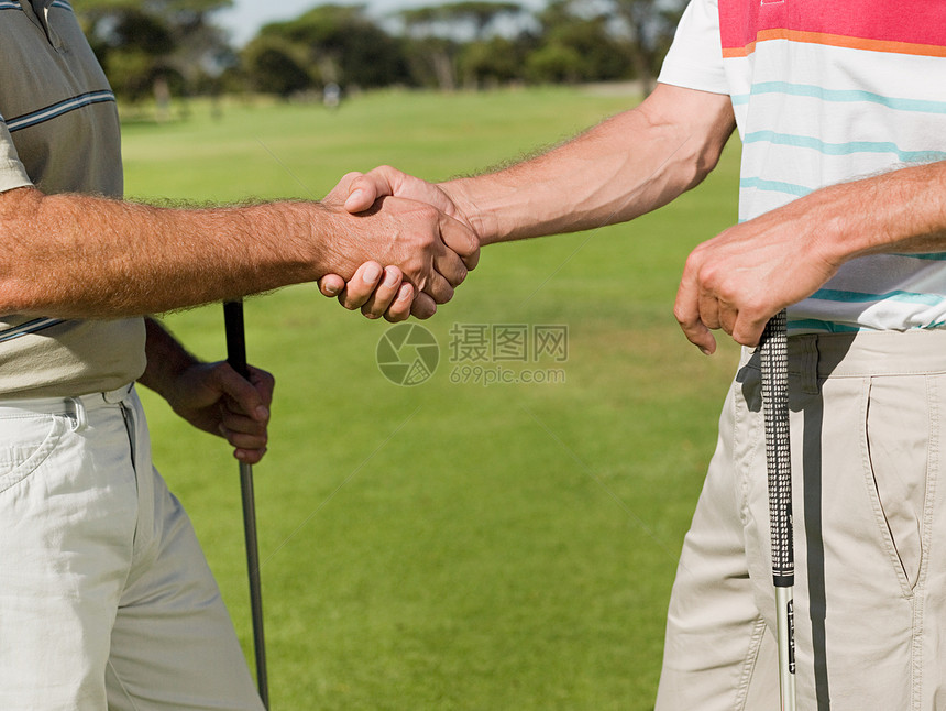 两个成熟的男人在高尔夫球场上握手图片