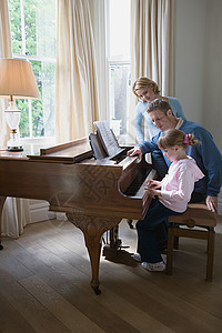 踩着凳子女孩父母带着女儿弹钢琴背景
