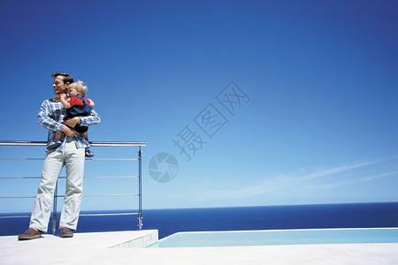父亲抱着孩子欣赏大海图片