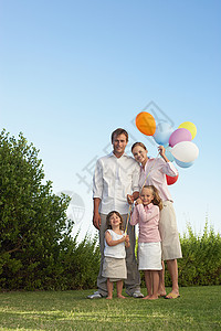 拿着气球站在花园里的家庭图片