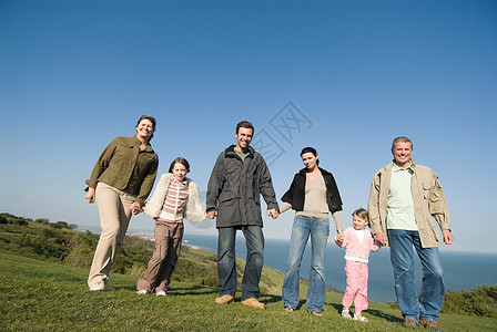 在青草丛生的小山上牵着手的一家人图片