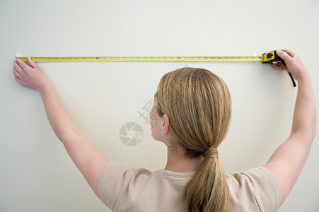 测量墙壁的女人图片