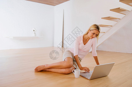 光脚地板女人在地板上用笔记本电脑背景