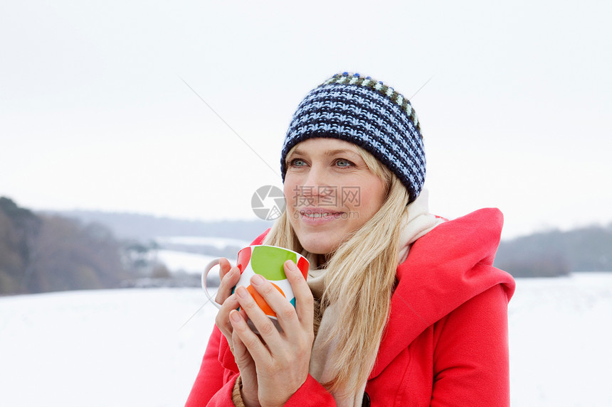 在雪地里喝热饮料的女人图片
