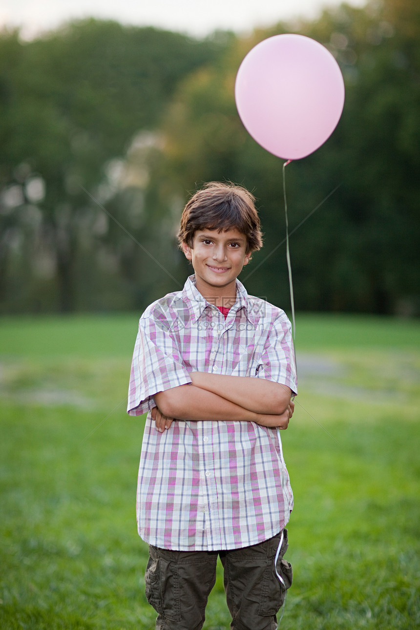 男孩在生日聚会上拿着粉红色的气球图片