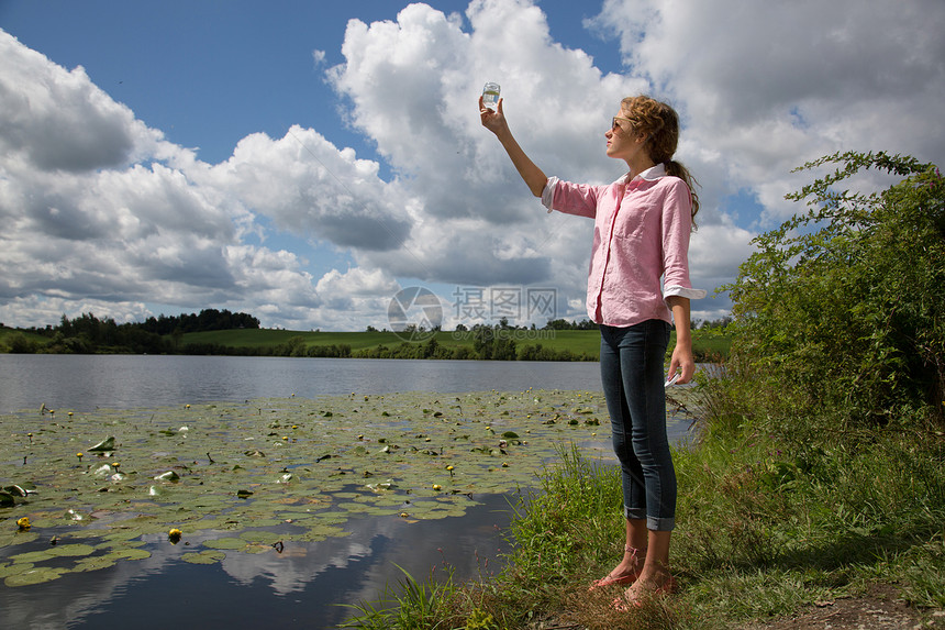 女孩拿着玻璃罐站在湖边图片