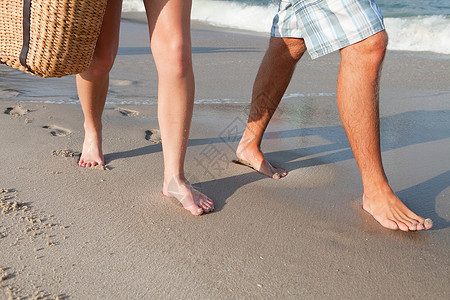 在海滩上散步的夫妇的腿图片