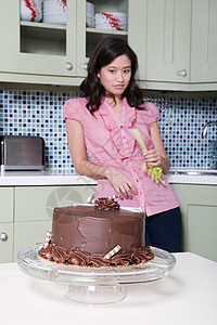 年轻女子吃芹菜看着巧克力蛋糕图片