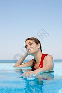 红色挂脖泳衣游泳池里的年轻女子的肖像背景