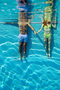 年轻夫妇在游泳池里手拉着手图片