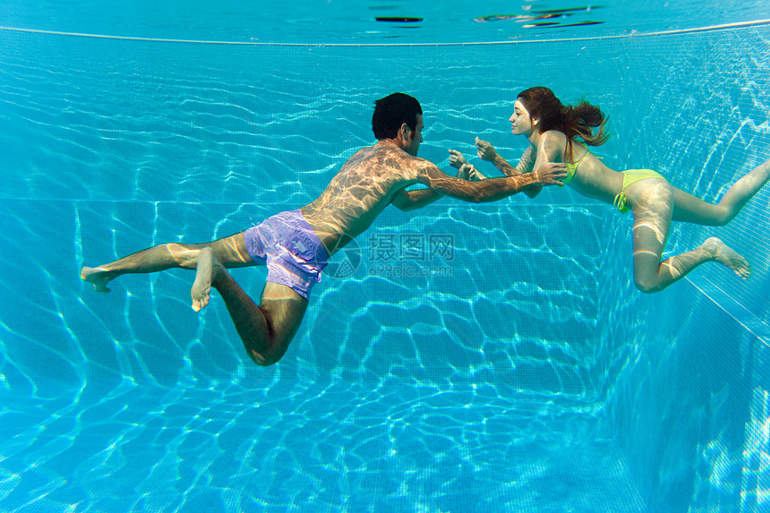 年轻夫妇在游泳池游泳图片
