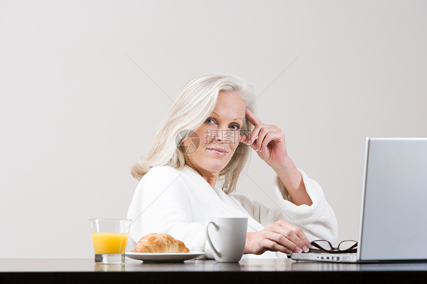 中年妇女在早餐时间使用笔记本电脑图片