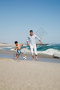 父子俩在海边踢足球背景图片