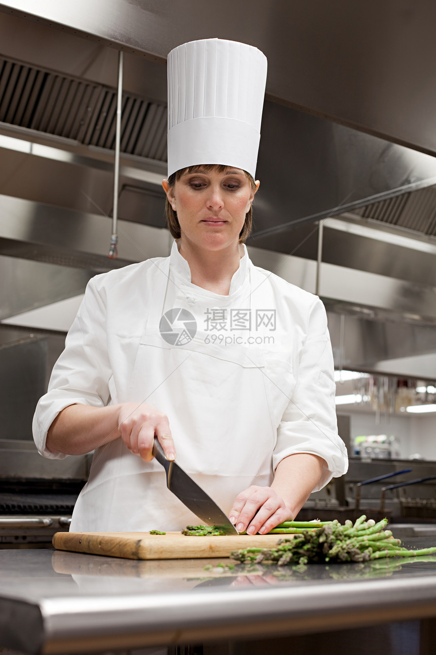 女厨师在商业厨房切芦笋图片