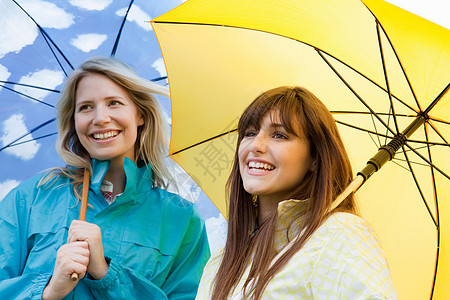 黄色的雨伞两个带伞的年轻女人背景
