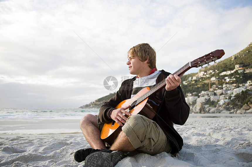 年轻人在海滩上弹吉他图片