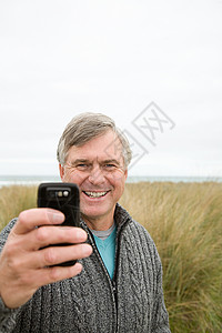 海岸边的男人拿着照相手机图片