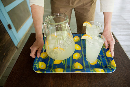 成熟的女人端着一盘柠檬水背景图片