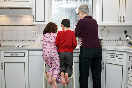 只有高加索种族带着男孩和女孩的祖母在厨房，后视图背景